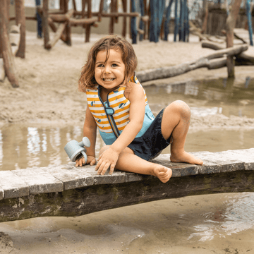 kind dat speelt op een brug met een kleurrijk zwemvest aan